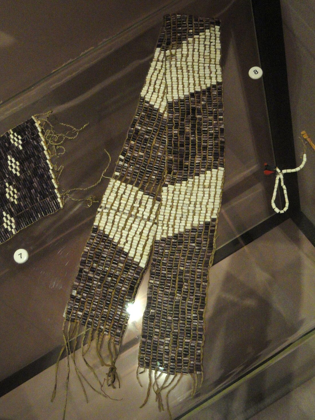 A purple and white wampum belt in a museum case